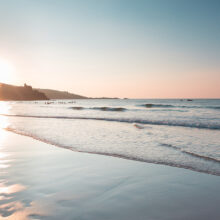 Surfers in the background are waiting for a wave, beach at sunset, coast, shore in Newquay