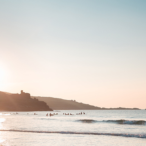 Cornwall beach at sunset, coast, shore with surfers Surfers in the background are waiting for a wave, beach at sunset, coast, shore in Newquay